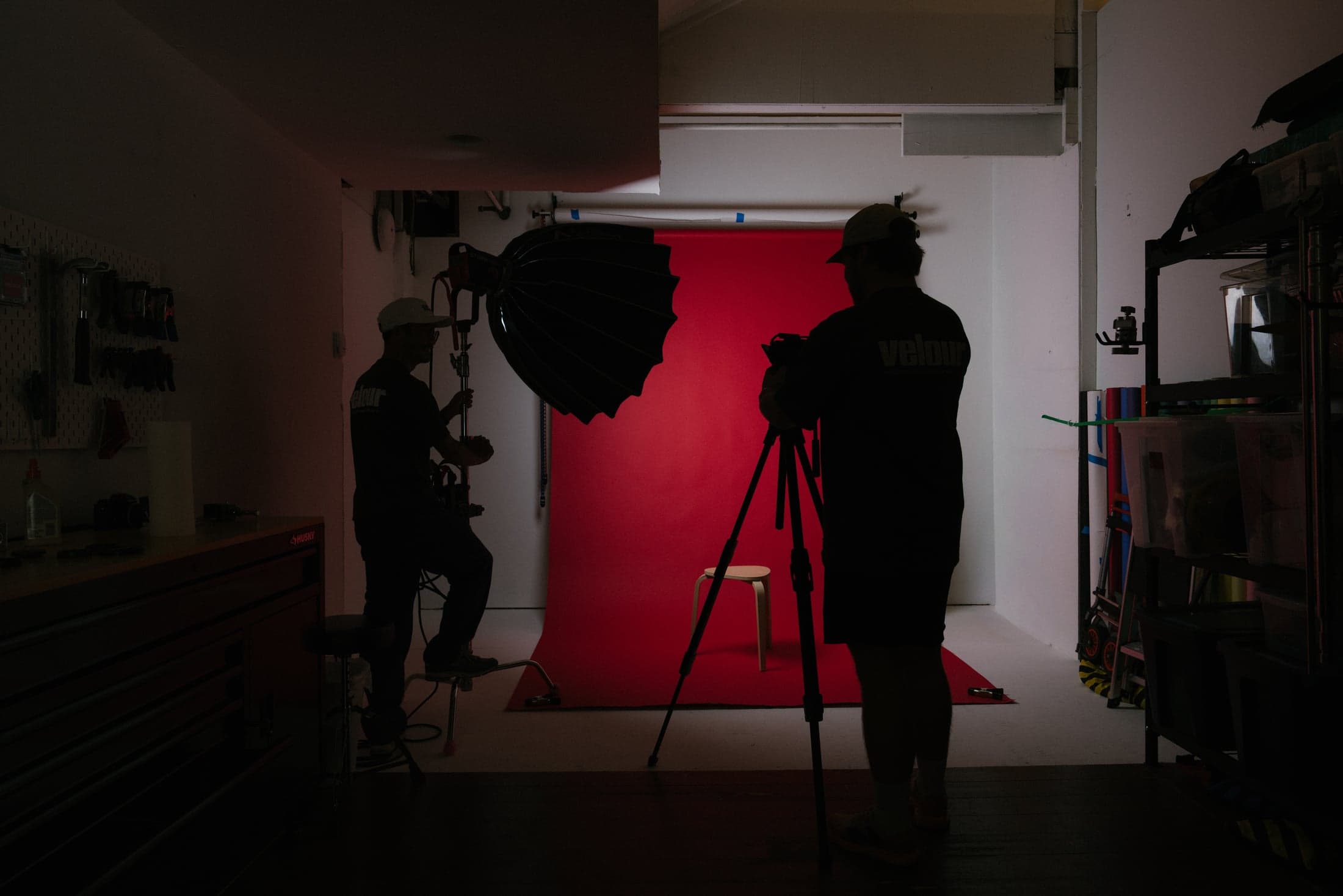 The Velour team setting up a camera and lighting against a red studio backdrop.