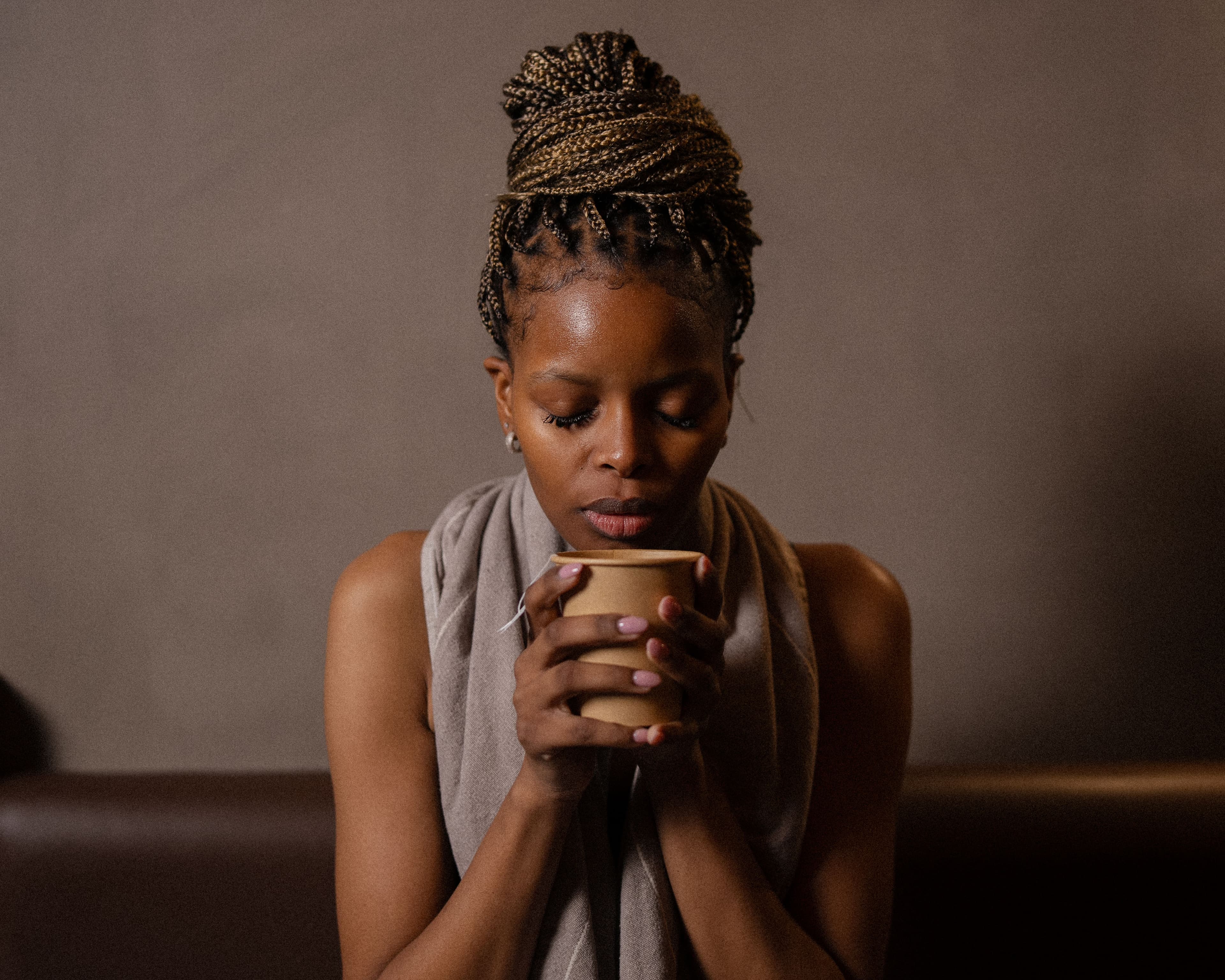 A woman resting after a wellness session while holding a warm cup in both hands.