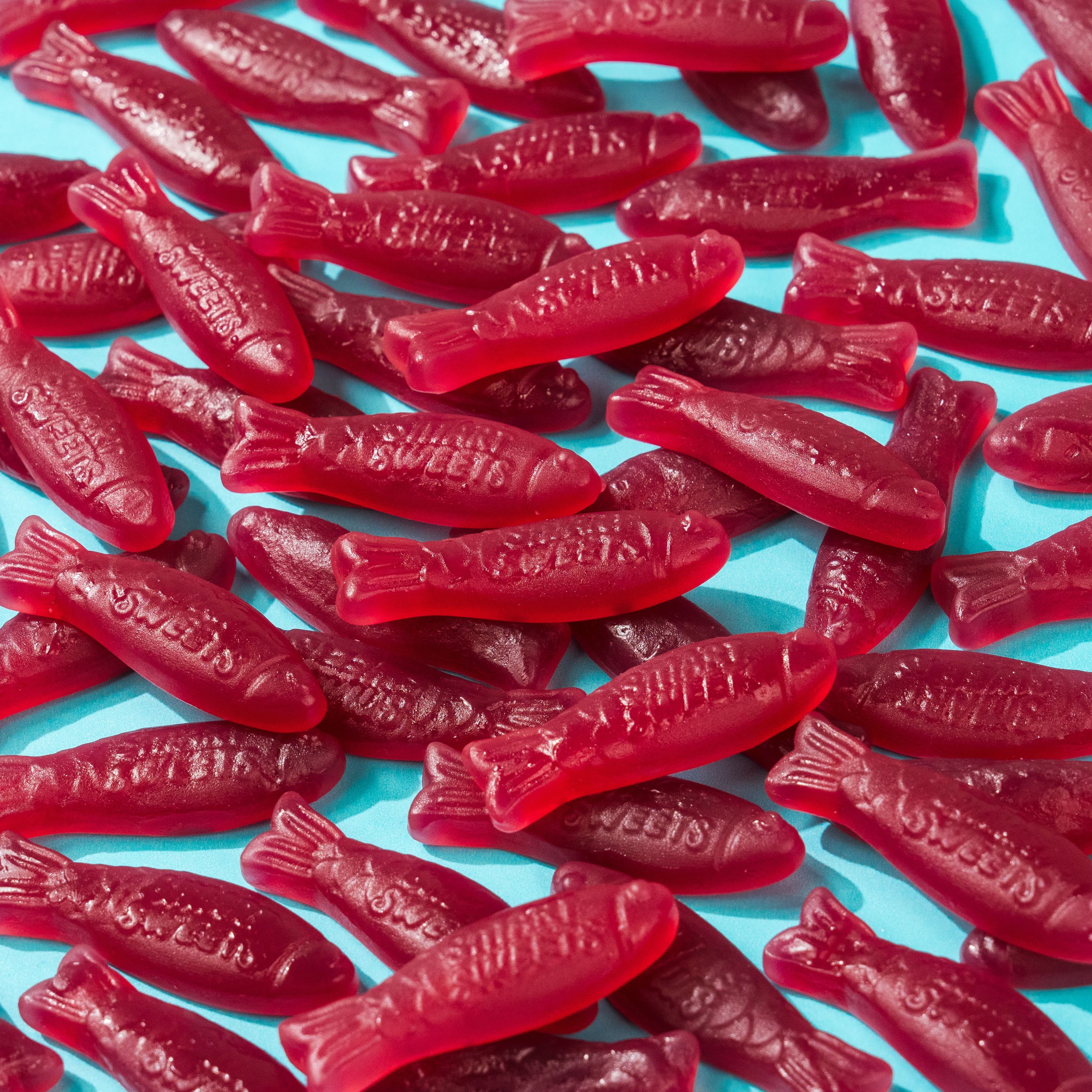 A repeating field of bright red SmartSweets gummy fish on turquoise.