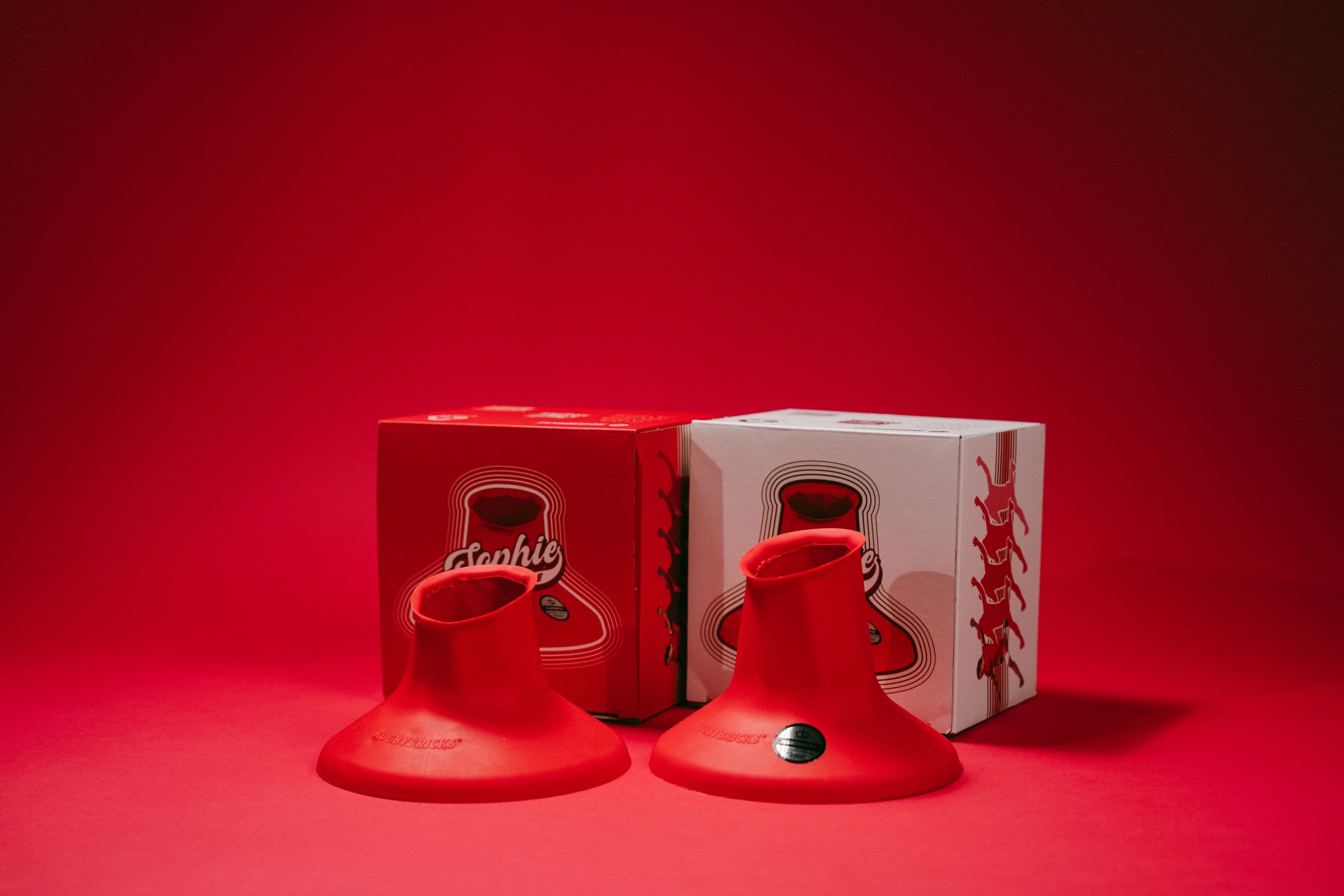 Two red Rugby Bricks signature kicking tees with red and white Sophie-branded boxes.