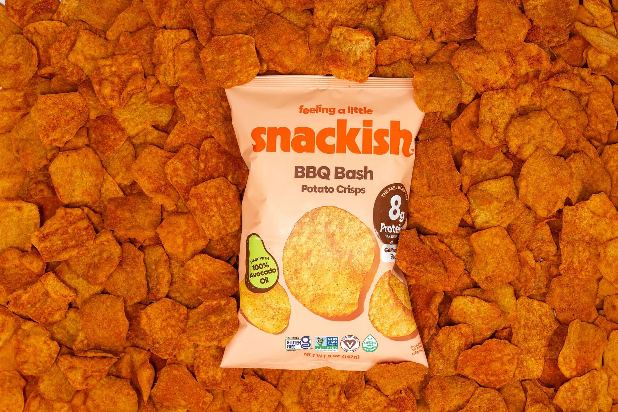 A bag of Snackish BBQ Bash potato crisps surrounded by barbecue-seasoned crisps.