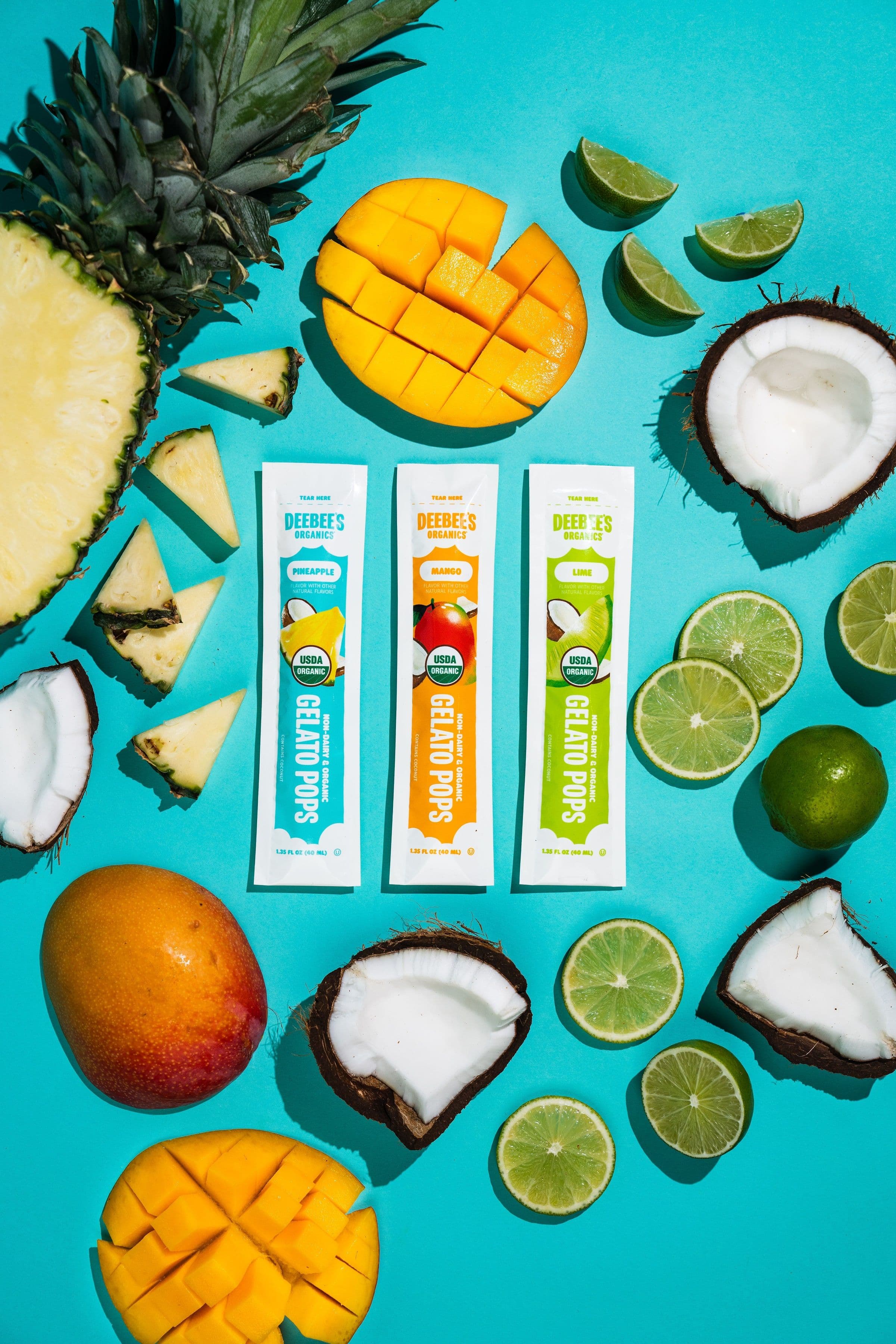 DeeBee’s SuperFruit freezies surrounded by pineapple, mango, coconut and lime on a turquoise background.