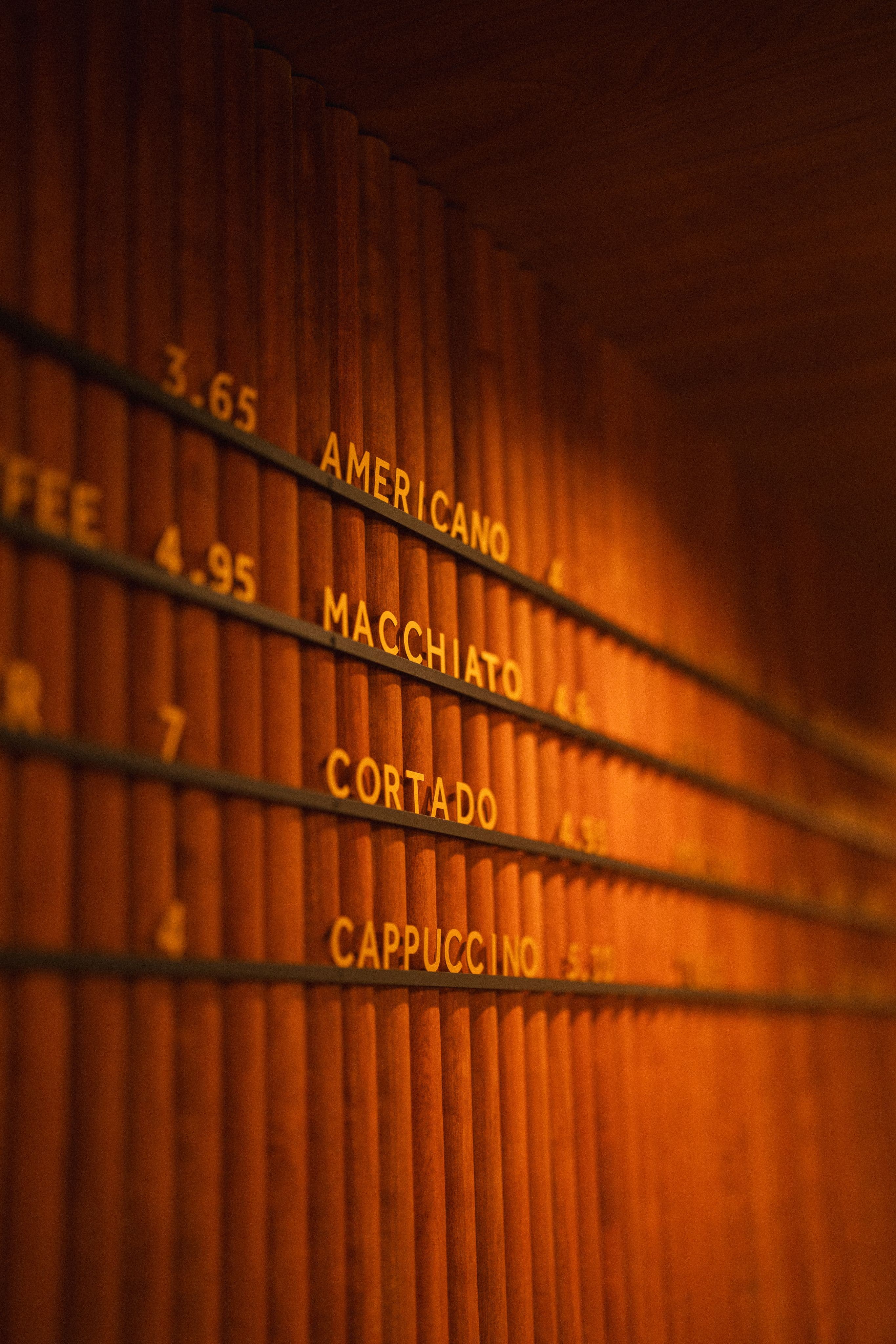 Slo Coffee's illuminated menu wall in warm amber light.