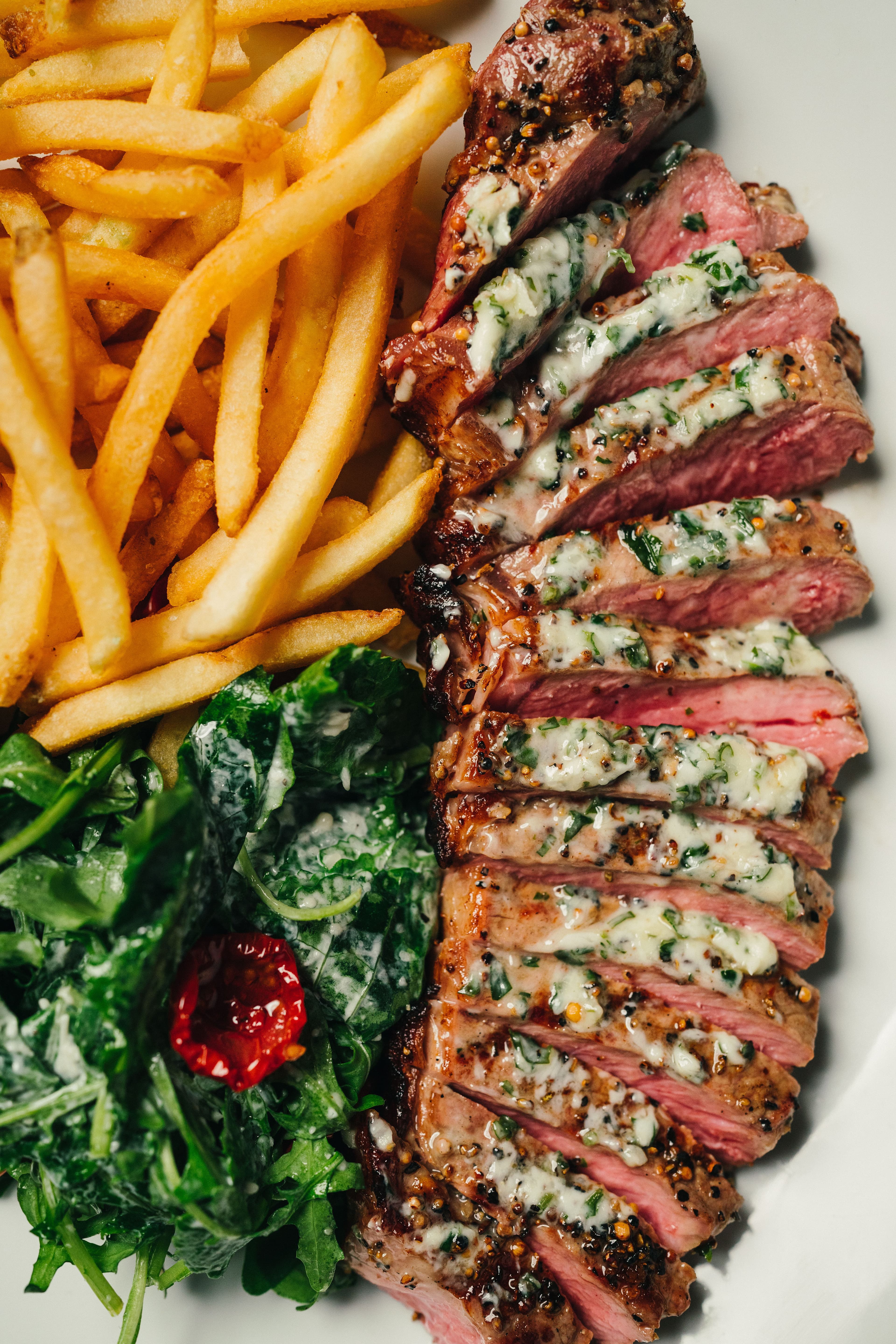 Sliced grilled steak served with golden fries and dressed greens.
