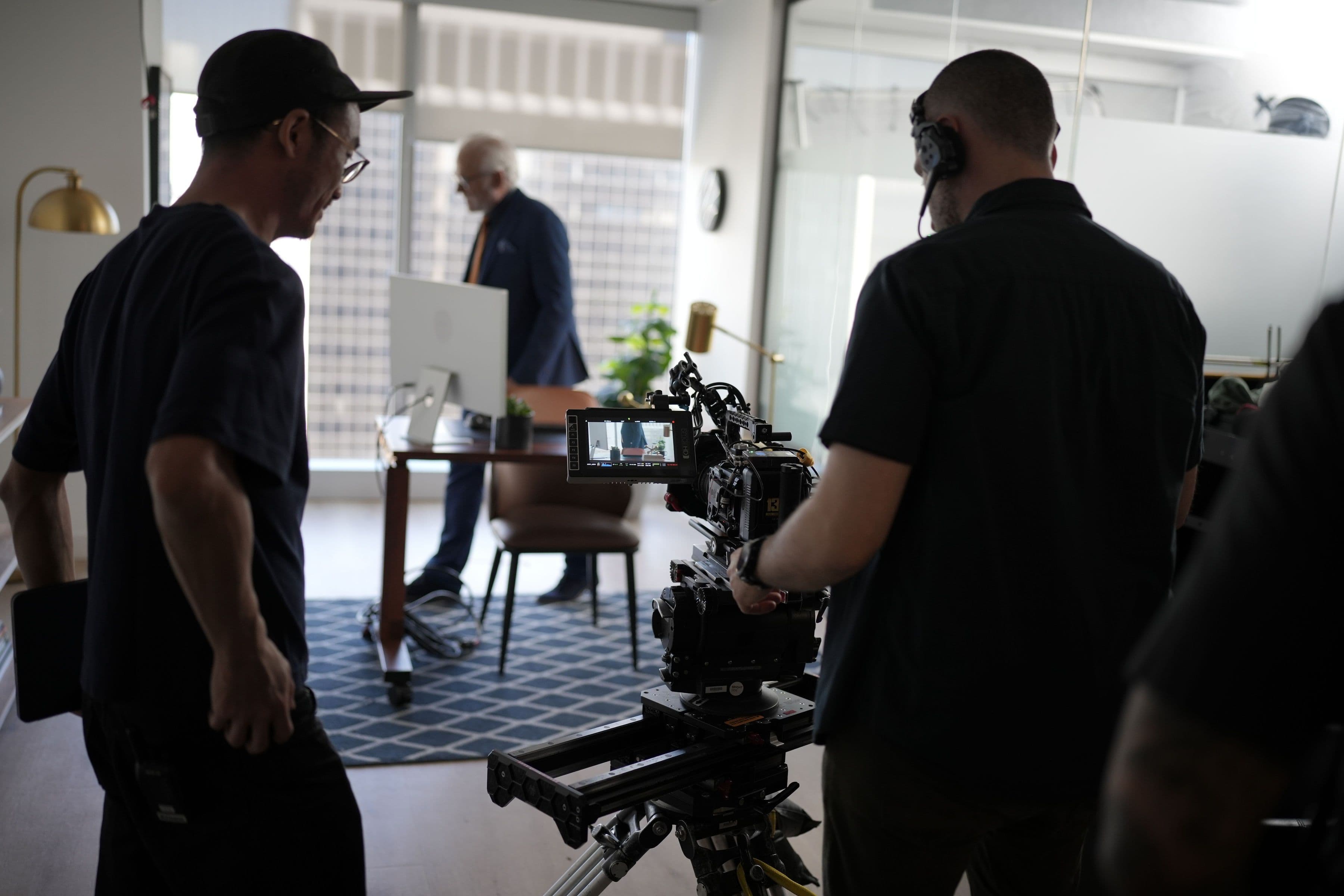 Two crew members operating a cinema camera during an office scene.