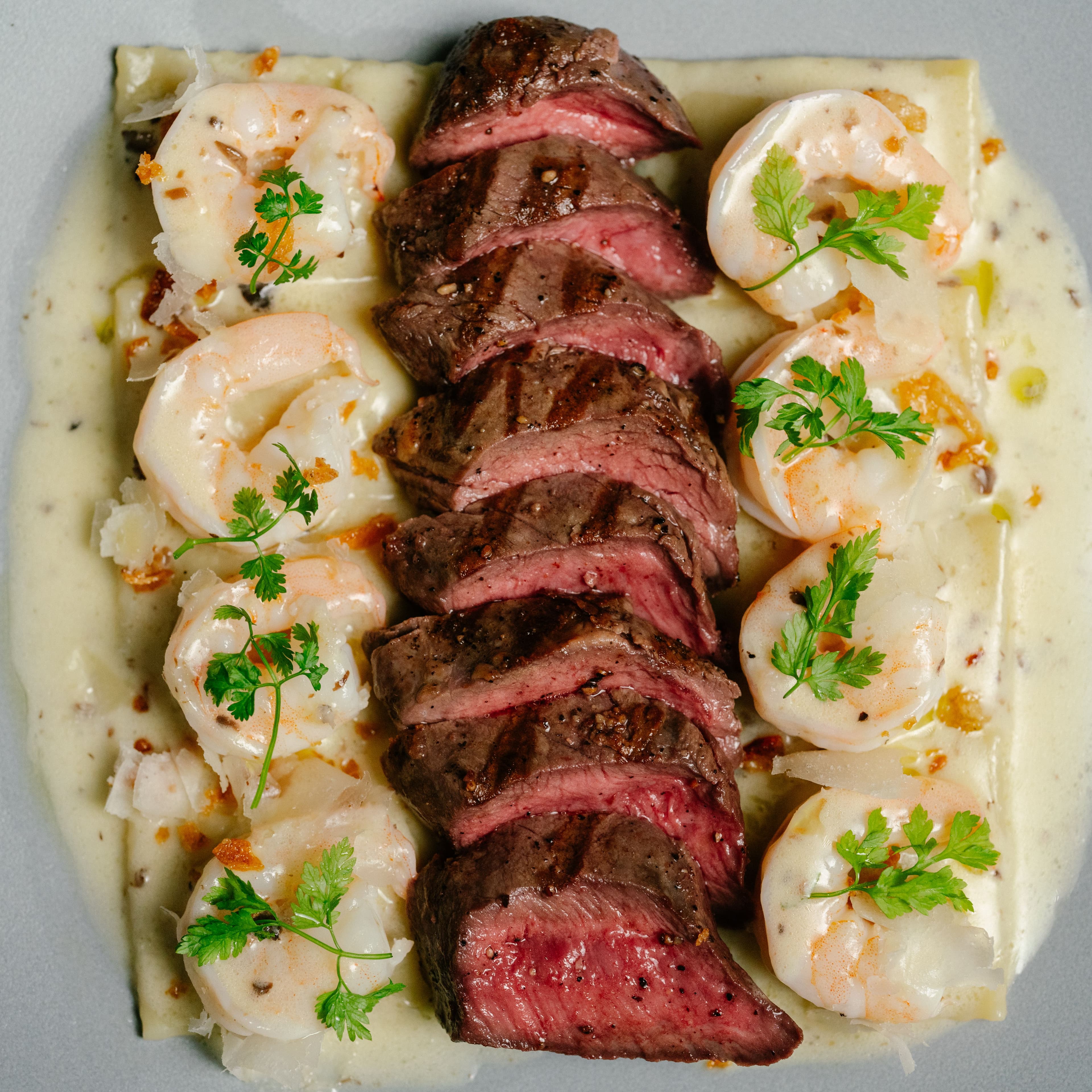 Sliced steak and seared scallops arranged on a rectangular serving plate.