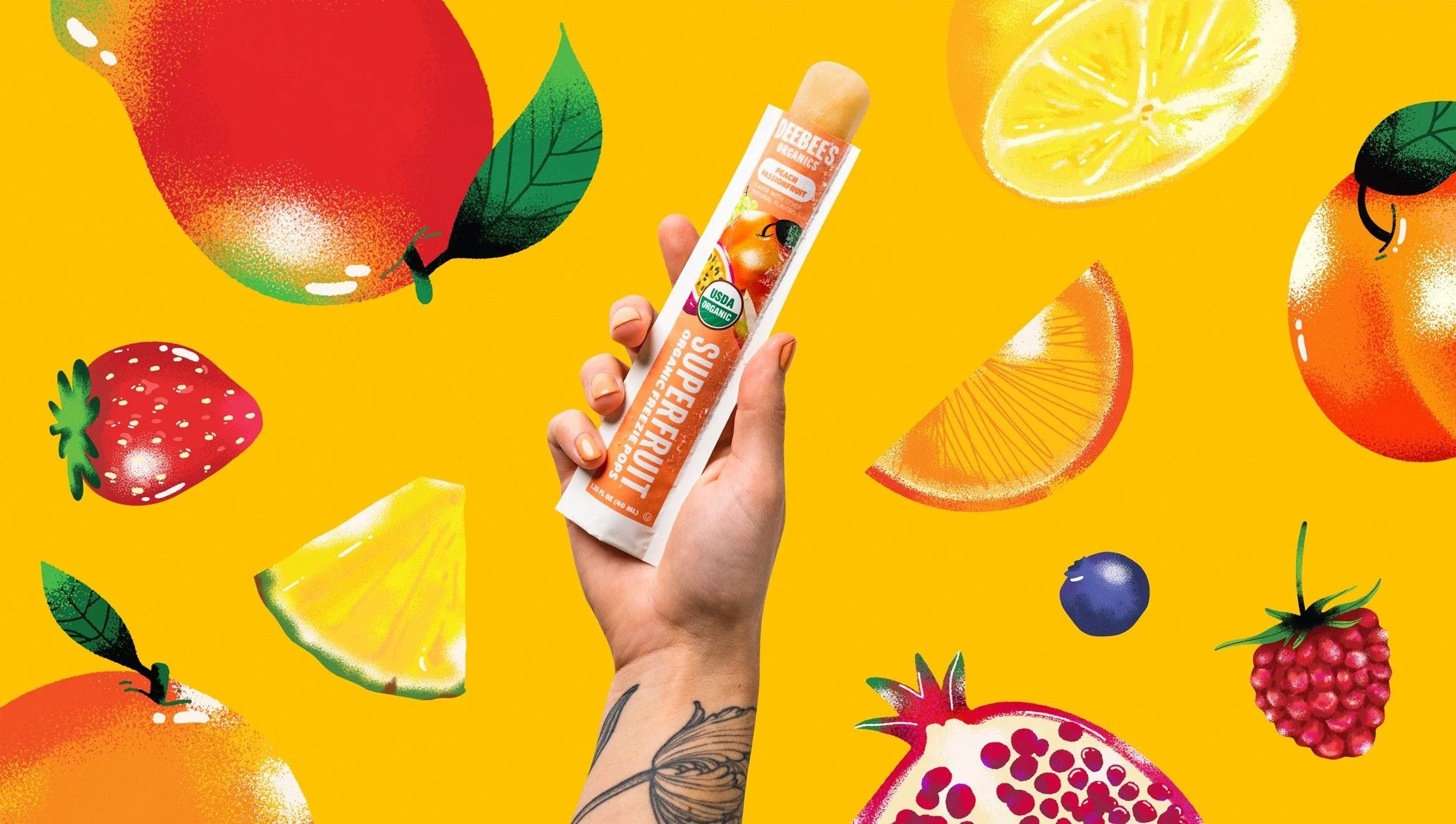 A hand holding a DeeBee's Super Fruit Freezie against a vivid fruit collage.