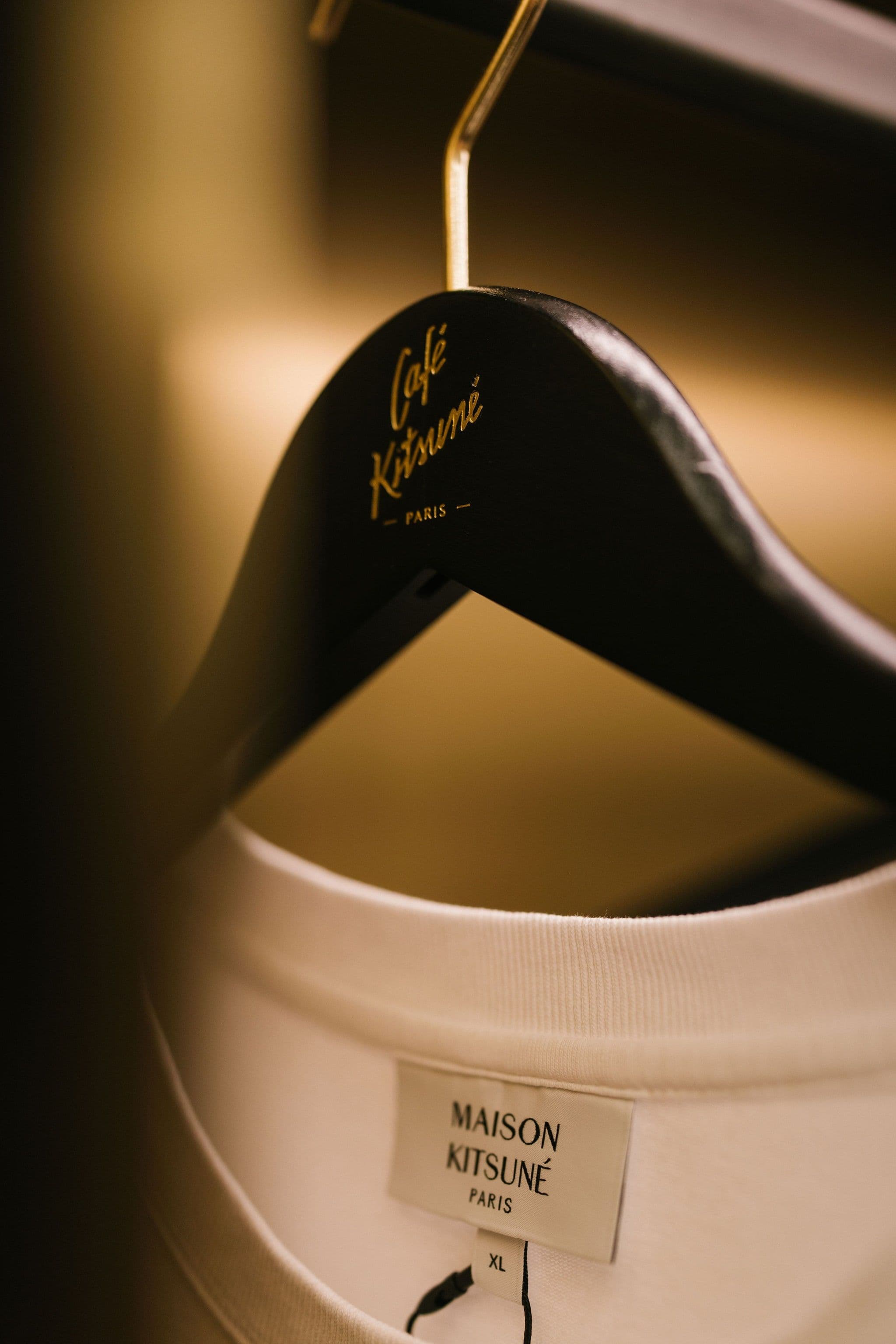 Close-up of a white Maison Kitsuné T-shirt on a branded hanger.