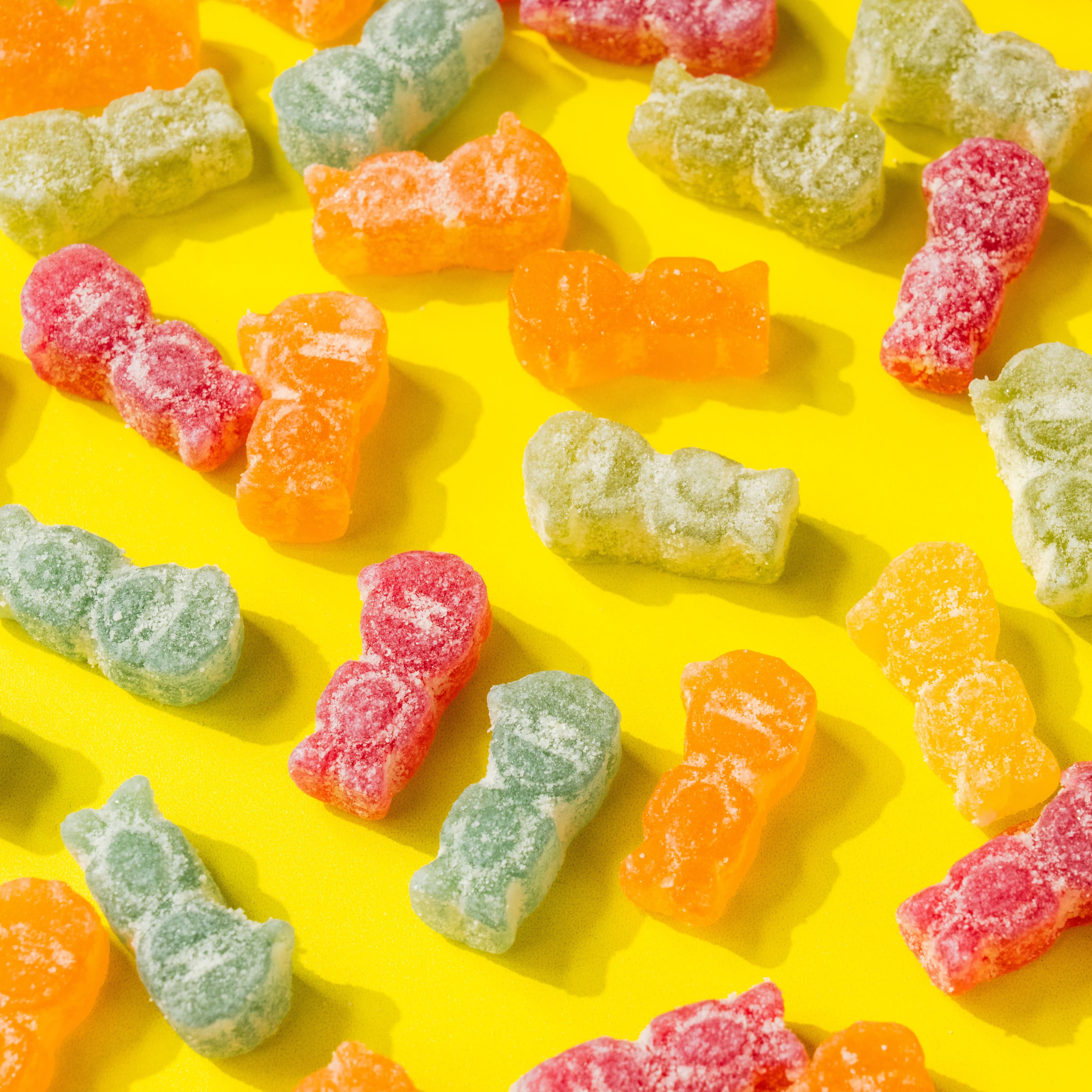 Colourful sugar-coated SmartSweets candies scattered across a bright yellow set.