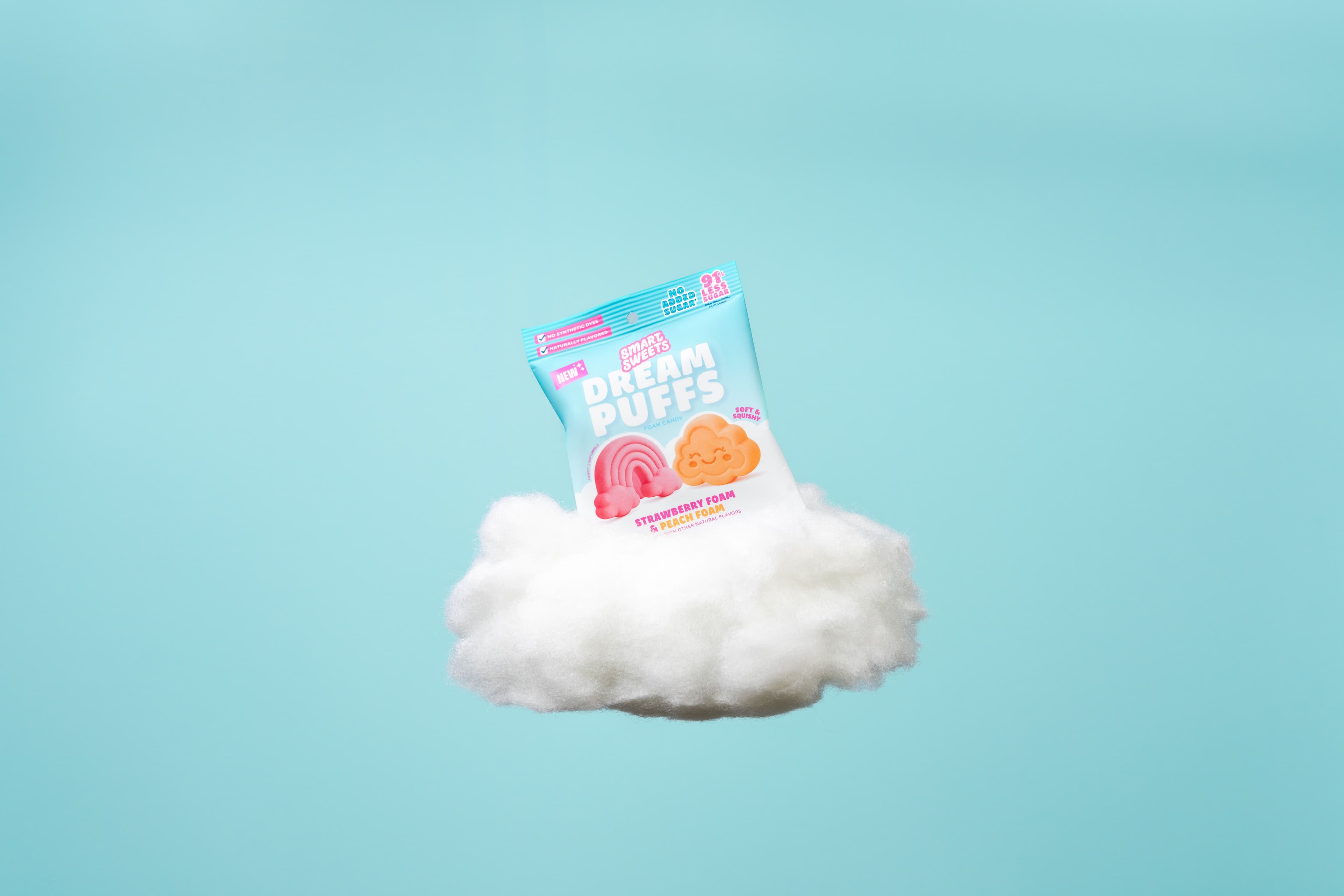 A SmartSweets Dream Puffs package floating on a small white cloud against blue.