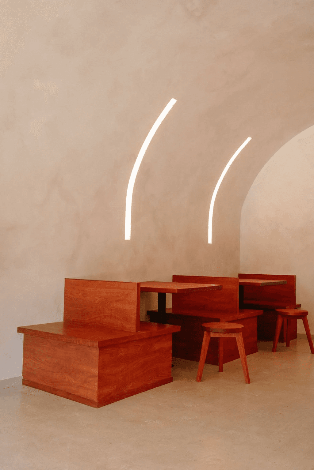 Warm timber benches beneath curved white light in the Slo Coffee space.
