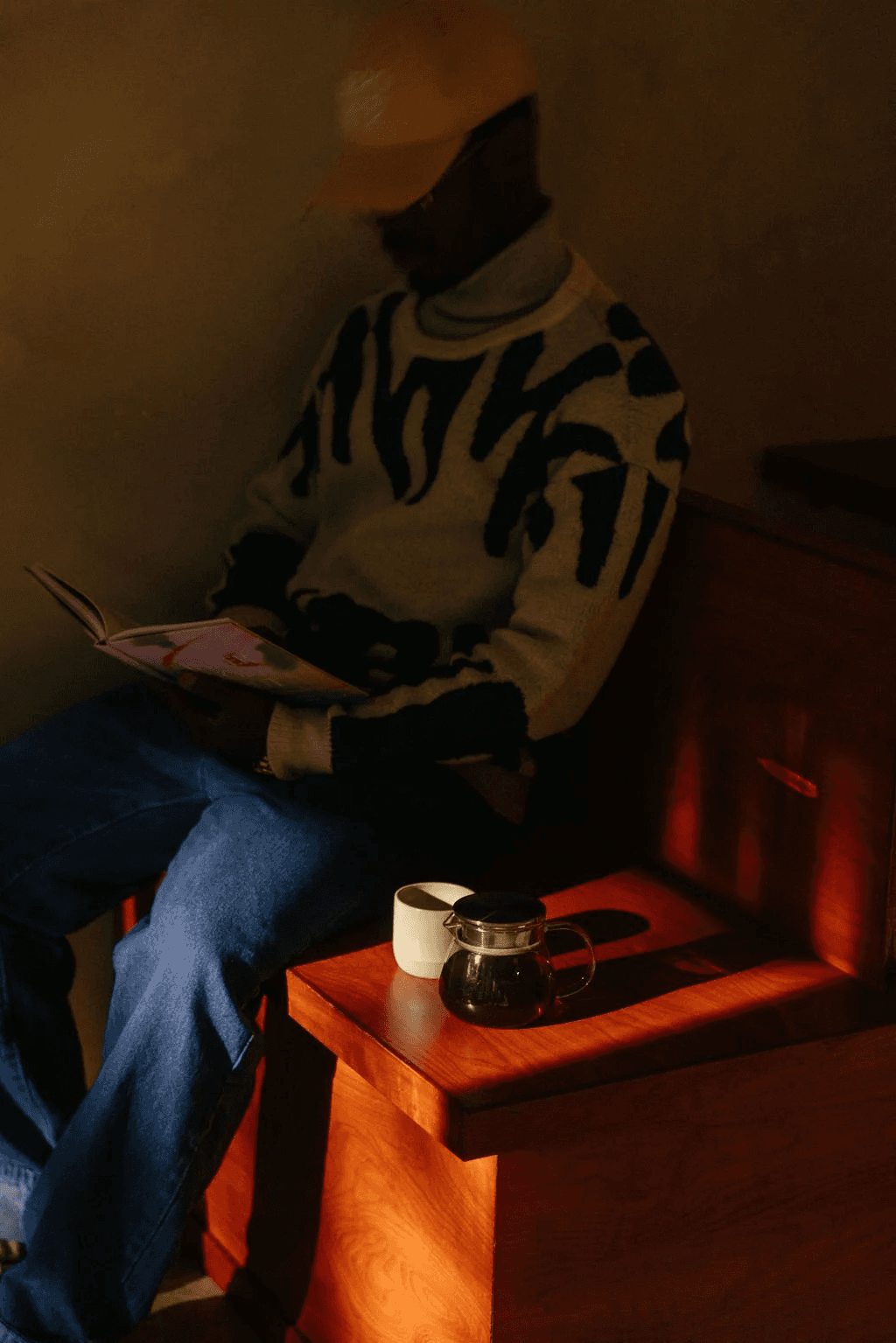 A guest seated in a narrow beam of warm light at Slo Coffee.