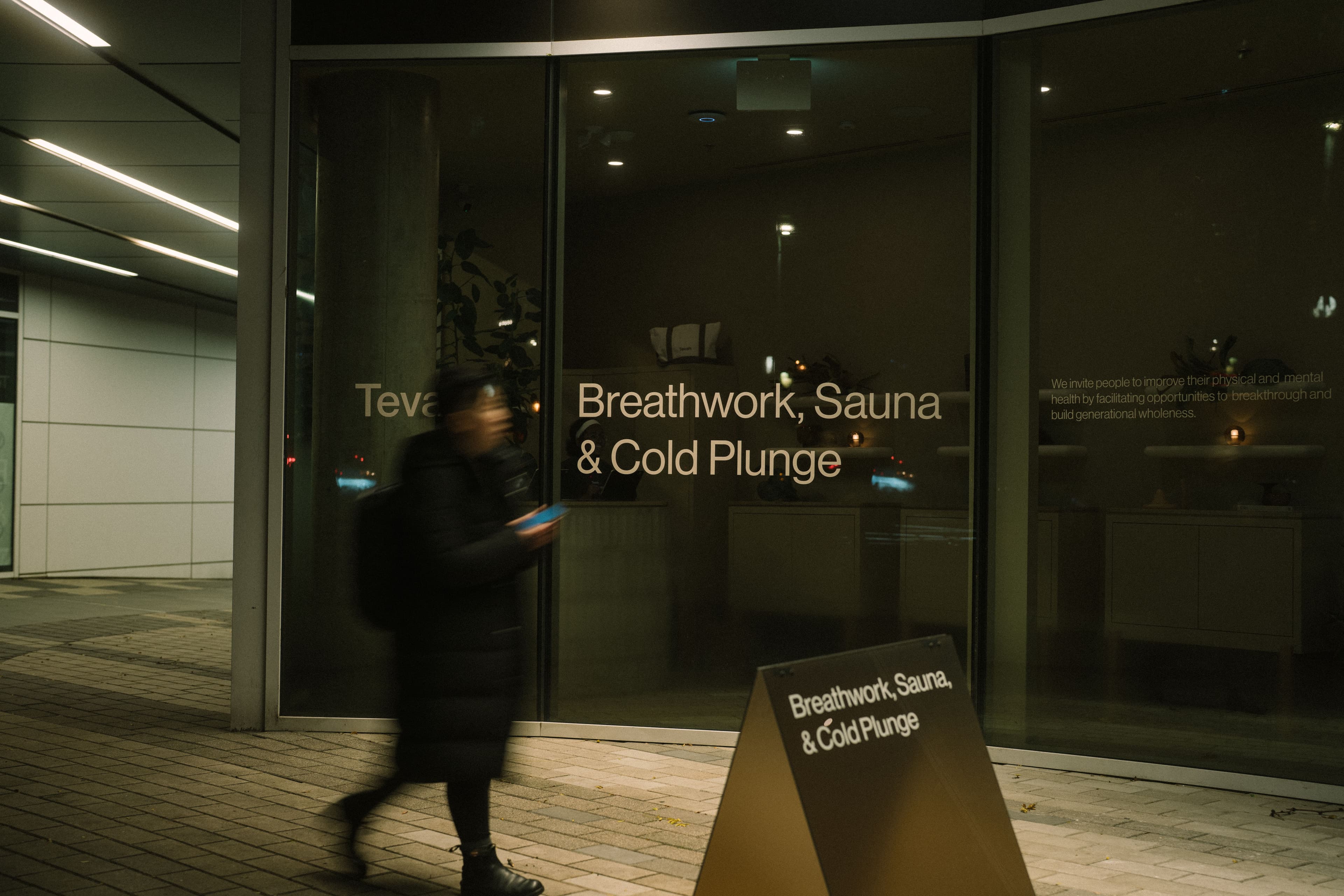 A passerby moving past the Tevah Wellness entrance at night in Vancouver.