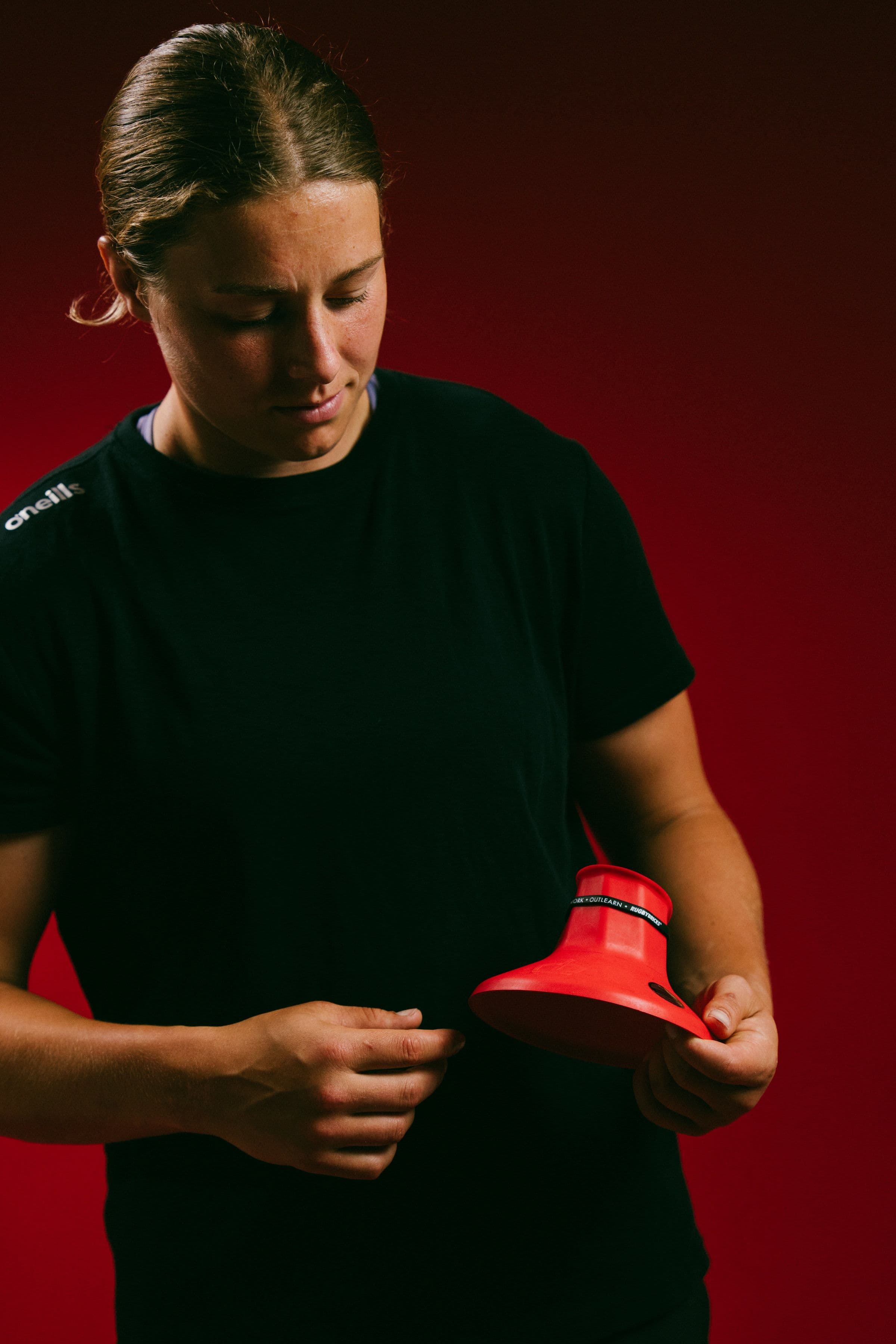 Sophie de Goede looking down at a red signature kicking tee in her hands.